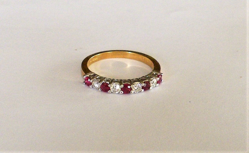 a ruby and diamond half hoop ring set in 18 carat gold